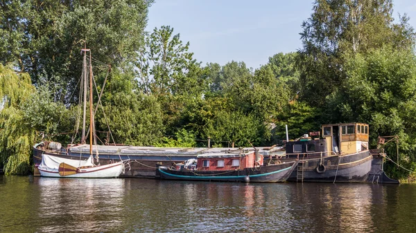 A big old barge, a sailboat and a cabin boat on the side next to