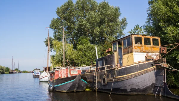 A big old barge, a sailboat and a cabin boat on the side next to — Stok fotoğraf