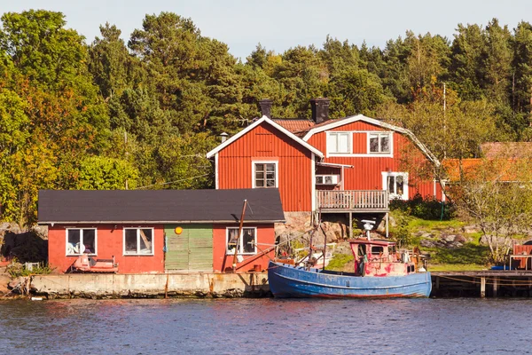 Rote Ferienhäuser und Fischerboot in Südschweden — Stockfoto