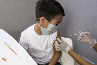 Gri arka planda gülümseyen çocuk doktor. Beyaz gömlekli erkek doktor işaret parmağıyla işaret ediyor. Sağlık hizmetleri sağlık sigortası konsepti. Antiviral ilacı kopyalamak için boşluk kopyala