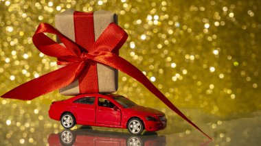Arkasında hediye olan kırmızı oyuncak araba. Noel hediyesi teslimatı konsepti. Altın Noel arkaplanı
