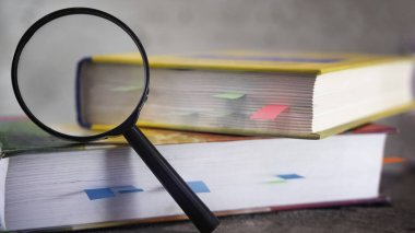 Büyüteç ve masada açık bir kitap..