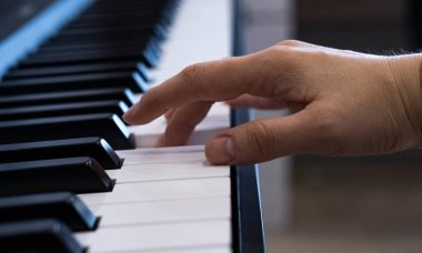 A female hand is playing the electronic digital piano at home. The woman is a professional pianist who arranges music using electronic piano keys. The musician practices keyboards and composes a clipart