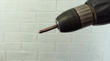 Küçük dönüşlü otomatik tornavida. Mobilyalar evde toplanıyor. Elektrikli matkap, tahta bir yüzeye vidalayarak dikey görüntüyü kapatır.