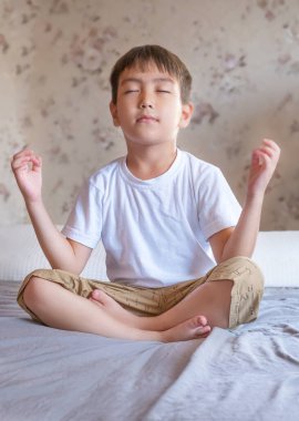 Yatağında, nilüfer pozisyonunda, buruşuk yatağıyla oturan tatlı çocuk..