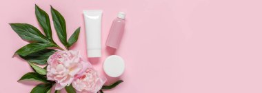 Düz kompozisyon, kozmetik ürünleri ve pembe arka planda şakayık çiçekleri vardı. Web afişi. Uzayı kopyala Üst görünüm