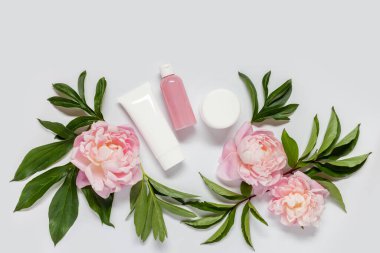 Beyaz arka planda kozmetik ürünleri ve şakayık çiçekleri olan düz bir kompozisyon vardı. Boşluğu kopyala