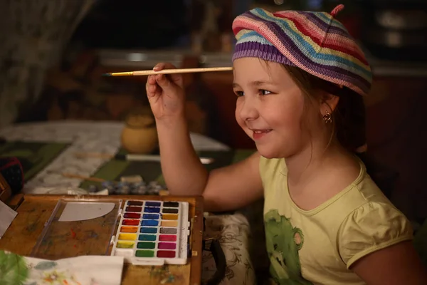 Fille artiste dans un béret de couleur peint un portrait de maman sur un chevalet, mise au point sélective — Photo