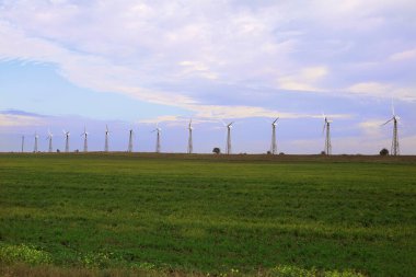 Rüzgâr türbinleri mavi gökyüzüne karşı bir tarlada duruyor