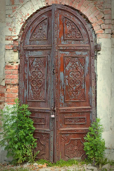 Duvarın arka planında antik demir kemerli bir kapı.