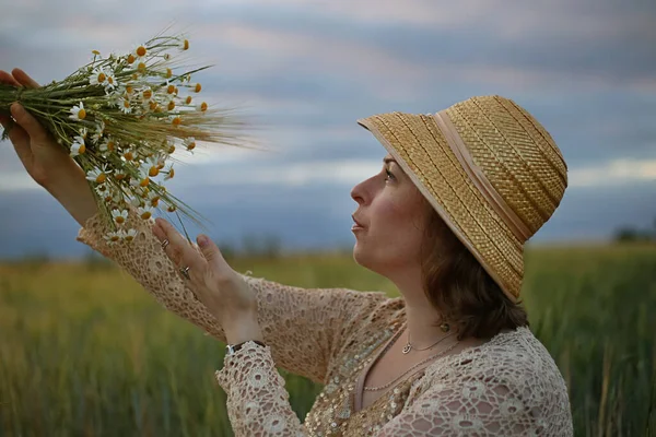 Güneşli yaz gününde şapkalı ve papatya çiçekli güzel bir kız. Papatya tarlasında bir kadın