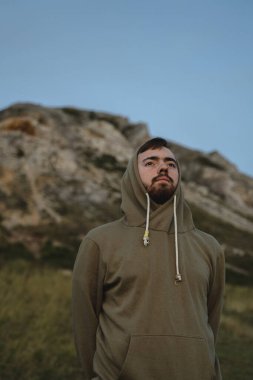 Yeşil kazaklı genç bir adam sırtı dağa dönük duruyor ve bozkırların genişliğine bakıyor, çıplak gökyüzüne.