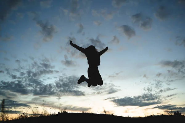 silhouette of a girl jumping against a sunset background, freedom in the mountains, love and reunion with nature