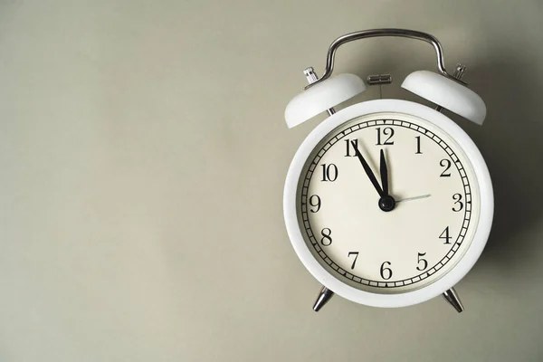 an alarm clock with a dial lies on a gray background, the time brings it closer to a new day