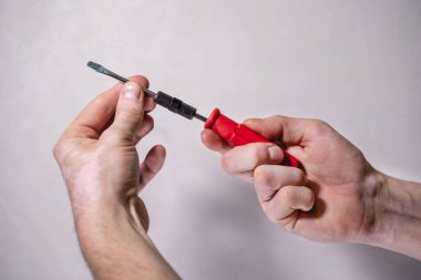 Erkek eller çift taraflı kombinasyon tornavida tutuyor, kırmızı saplı, beyaz arka plan, kemer işi