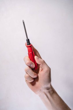 Kırmızı saplı bir tornavida tutan erkek el, beyaz arka plan, tamir işi
