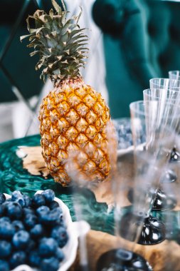 Güzellik salonunun açılışı için büfe masası, şampanya bardakları, meyveler, parlak sarı ananas, epoksi reçineli ahşap masa.
