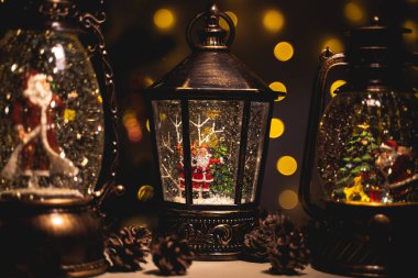 Kar yağışı efektli ve içinde figürler olan Noel fenerleri.