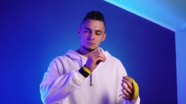 Beyaz kapüşonlu genç adam elinde altın bir top tutuyor.