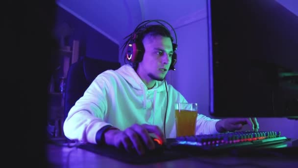 Gamer en auriculares con micrófono juega videojuegos en línea — Vídeo de stock