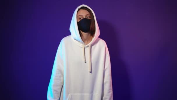 Jonge vrouw in witte hoodie en zwart medisch masker — Stockvideo