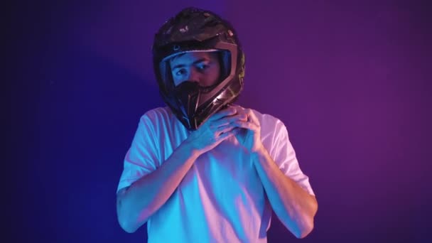 若い男は彼の頭の上にオートバイのヘルメットを置きます — ストック動画