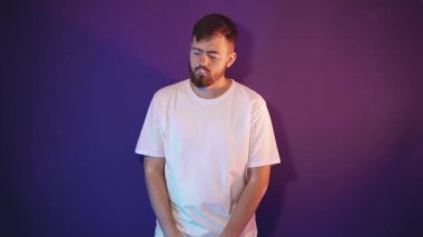 Beyaz tişörtlü sakallı bir adam elinde elektronik bir sigara tutuyor.