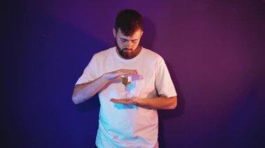 Sakallı genç adam elinde kum saati tutuyor.