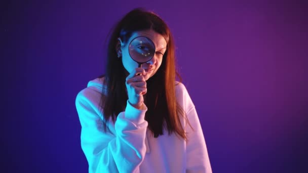 Junge Frau im weißen Kapuzenpulli hält eine Lupe in der Hand — Stockvideo