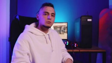 Rastalı genç adam bilgisayarda oynar, kulaklıklarını çıkarır.