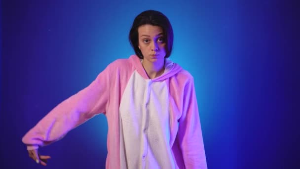 Ung kvinna i rosa pyjamas dansar roligt och sätter på en huva — Stockvideo