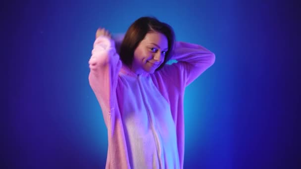 Positiv kvinna i rosa pyjamas sätter en huva på huvudet — Stockvideo