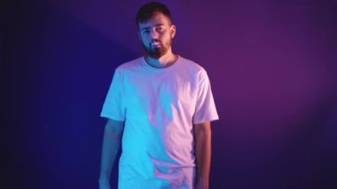 Beyaz tişörtlü genç sakallı adam elinde elektronik bir sigara tutuyor.