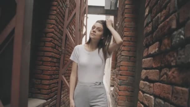 Leuke brunette vrouw loopt door een vintage tunnel met bakstenen muren — Stockvideo