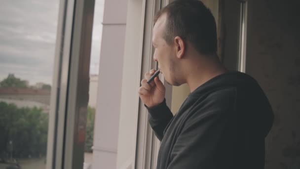 Hombre feliz en el balcón en casa mira a la distancia a través de la ventana — Vídeos de Stock