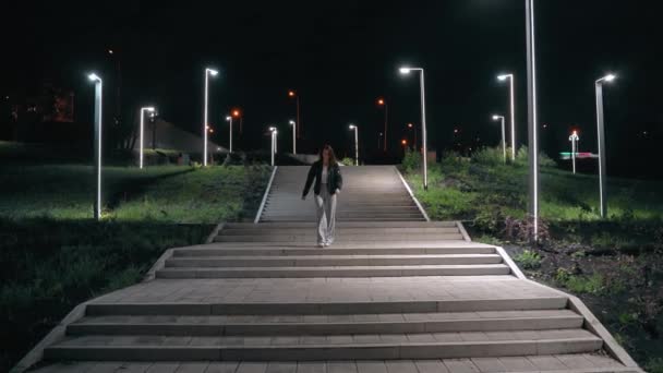 Alevli pantolonlu genç bir kadın merdivenlerden güzel bir yürüyüşle iniyor — Stok video