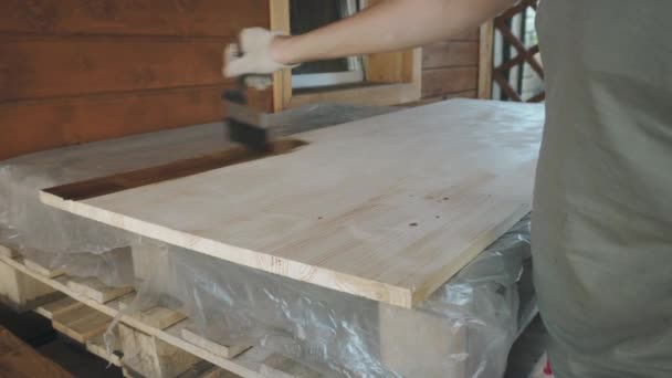 Uma mão de luva de homem cobre suavemente a mesa de madeira com um pincel — Vídeo de Stock