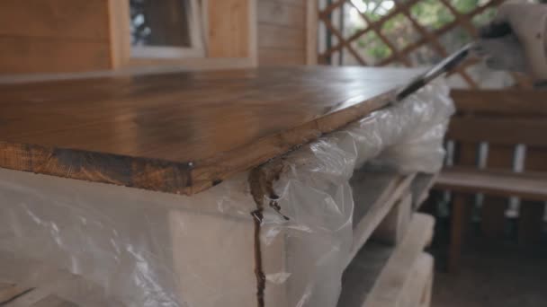 Jeune homme en uniforme de travail et gants couvre la table en bois — Video