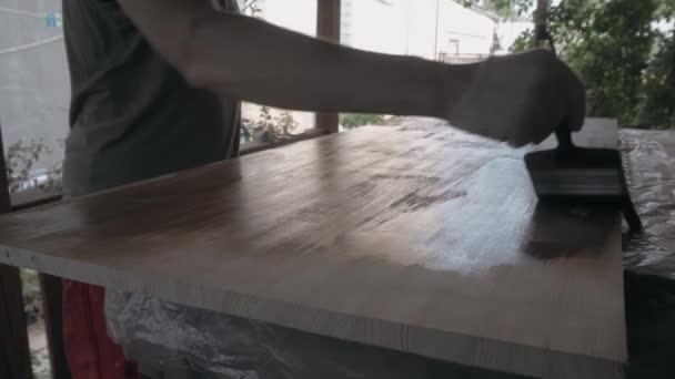 Young man in work uniform and gloves covers the wooden tabletop — Stock Video