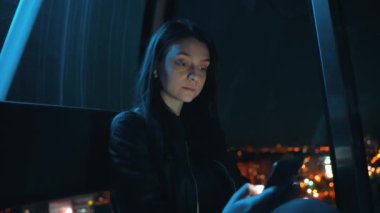 Esmer genç bir kadın dönme dolaba biner ve akıllı bir telefona biner.