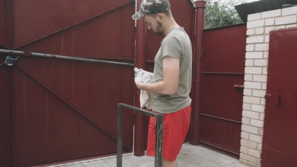 Jeune homme sérieux en uniforme de travail et gants verse dégraissant sur un chiffon — Video