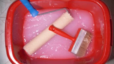 A mans hand holds a brush and soaks it in glue for gluing wallpaper