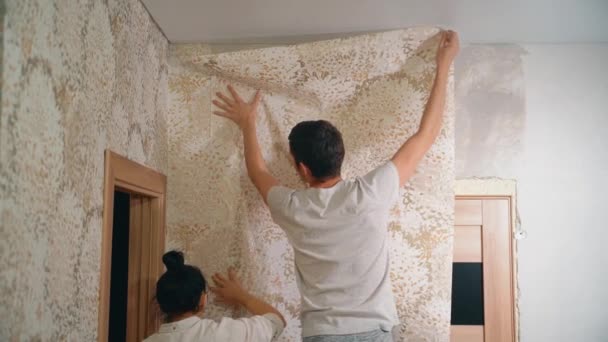 A man holds a wali in his hands and covers the putty wall with glue — Stock Video