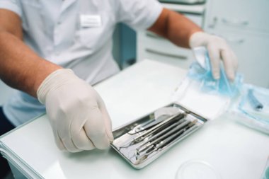 Doktor yardımcısı gümüş bir diş aleti tepsisi açar.