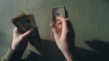 Mans hands are counting dollar bills on a nice green background