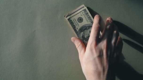 A stack of green banknotes lies on the table, then a mans hand picks them up — Stok video