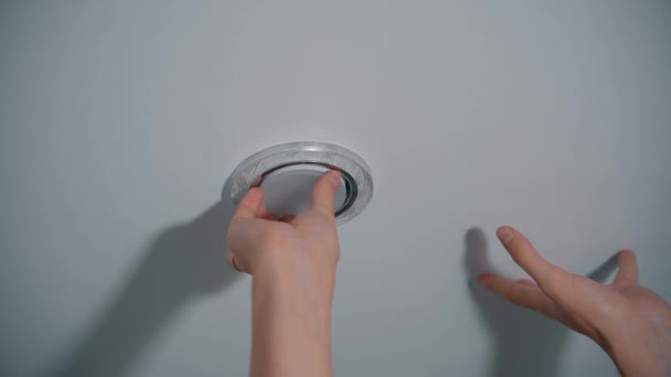 Männliche Hände schrauben eine Glühbirne in eine Spanndecke — Stockvideo
