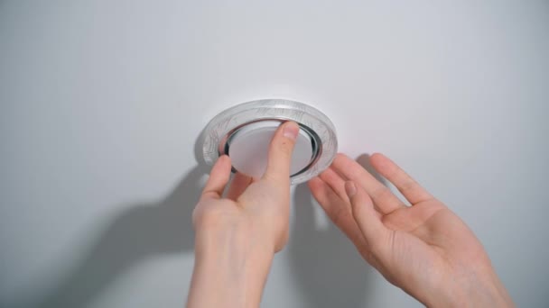 Male hands screw a light bulb into a stretch ceiling — Stok video