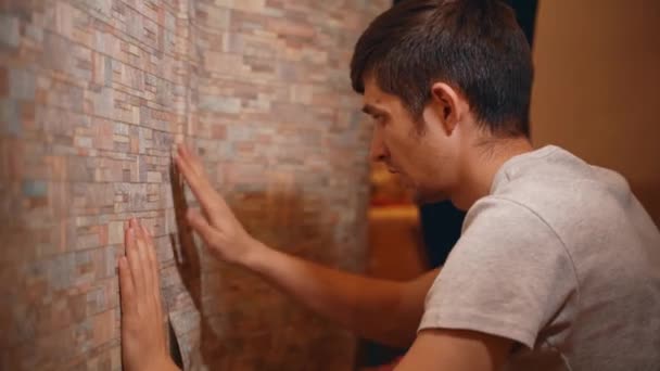 Serious man carefully glues wallpaper in a new house — Stock Video