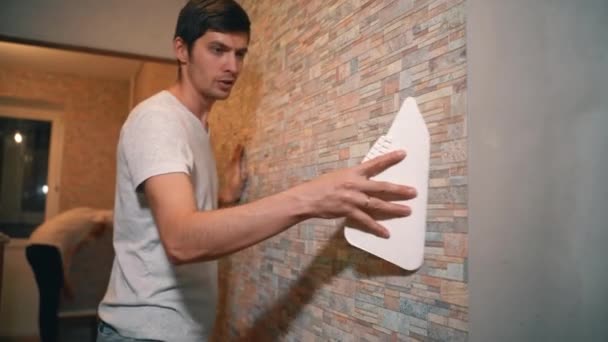 Una pareja casada hace reparaciones en su casa, pegando cuidadosamente el papel pintado, — Vídeos de Stock